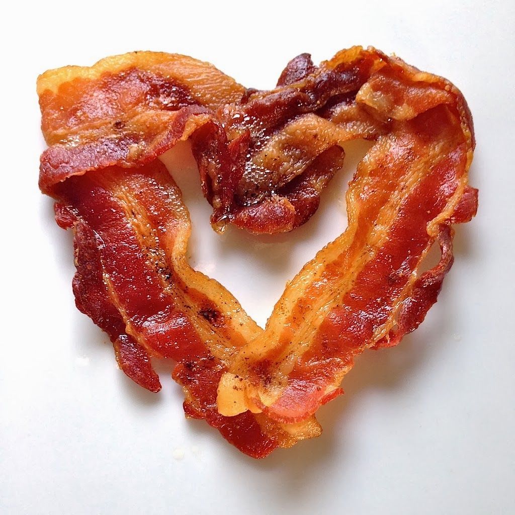 A picture of bacon placed in pieces in the shape of a heart.